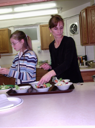 Thea Julien makes a salad with a Challenge team member during an event for Challenge parents