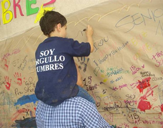 Un alumno del colegio escribe en el muro del recuerdo.