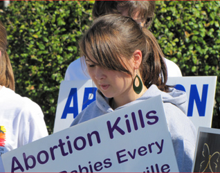 Mission Youth members hold signs in silent witness