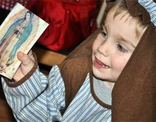 A little saint holds a picture of Our Lady of Guadalupe