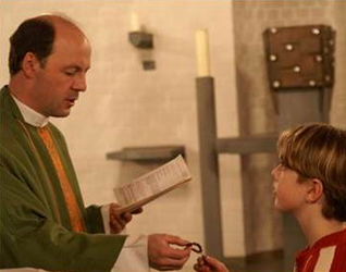 El P. Klaus entrega la corona del rosario a un niño durante las incorporaciones al ECYD en el noviciado de Bad Münstereifel.