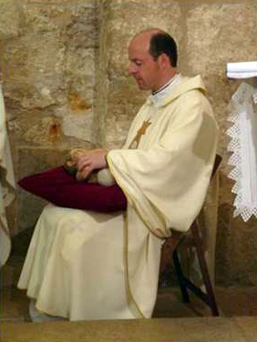 El P. Klaus Einsle, L.C., con el niño Jesús en sus brazos, en la capilla de la iglesia del nacimiento de Cristo en Belén.