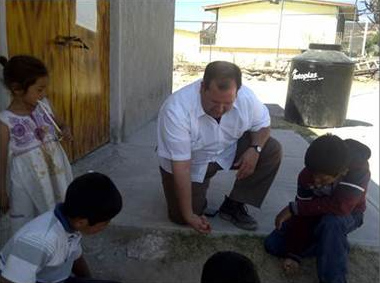 El P. Isidro juega canicas con un grupo de niños durante unas misiones.